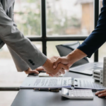 Deux hommes d'affaires se serrant la main, symbolisant un partenariat réussi grâce à l'utilisation stratégique de mots-clés commerciaux dans leur stratégie de marketing digital