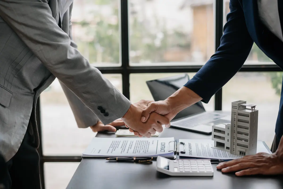 Deux hommes d'affaires se serrant la main, symbolisant un partenariat réussi grâce à l'utilisation stratégique de mots-clés commerciaux dans leur stratégie de marketing digital