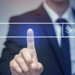 Un homme pointant du doigt une barre de recherche virtuelle, illustrant l'importance des mots-clés informationnels pour optimiser la visibilité d'un site web dans les résultats des moteurs de recherche.