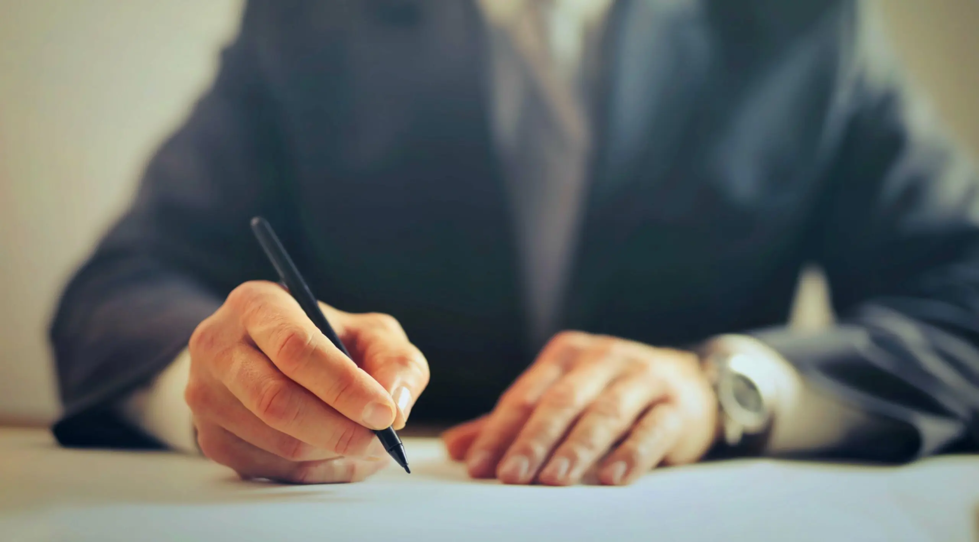 Un homme d'affaires signe un contrat, illustrant l'importance des mots-clés transactionnels pour convertir les visiteurs de site web en clients.